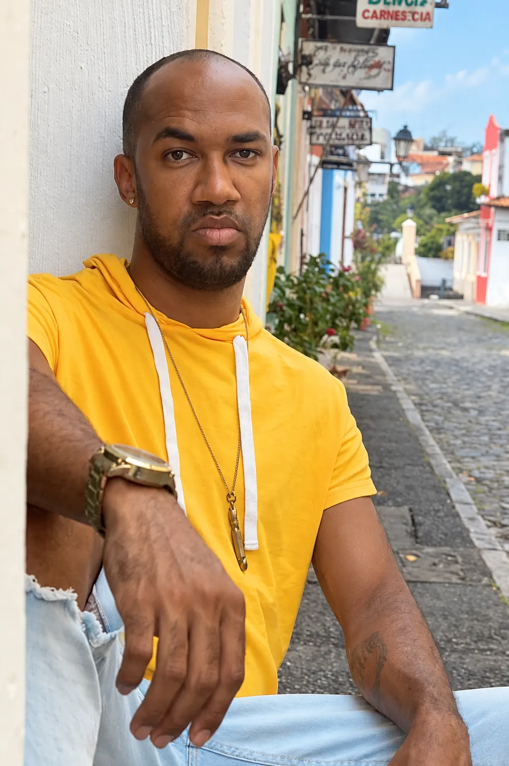 Homem negro sentado sozinho em uma rua de casario, ilustrando o artigo sobre a solidão do homem negro gay
